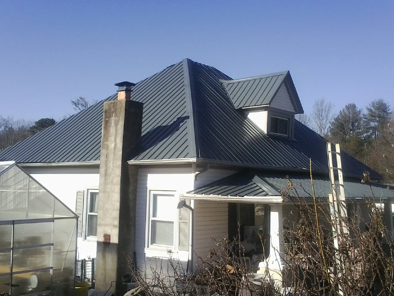 Dark blue standing seam metal roof on a white farmhouse with dormer — Slate & Tile Roof Repair by Roofing Brothers in Lake Oswego