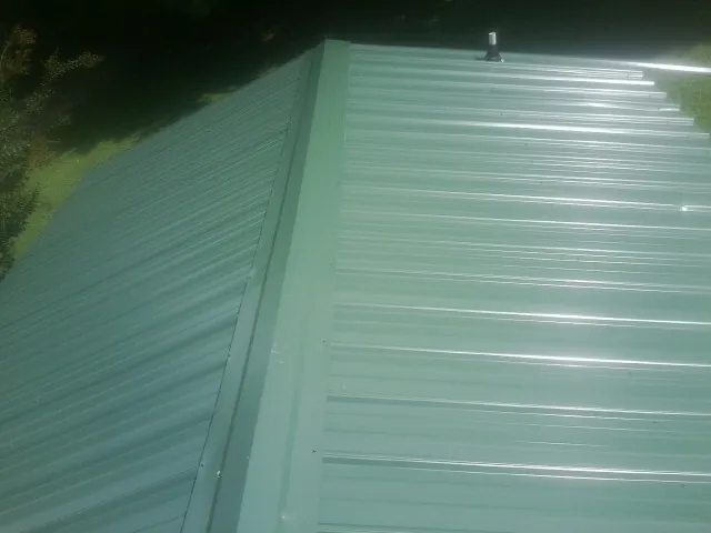 New green metal panels meeting at the ridge of a roof — Flat Roof Repair work by our crew in Lake Oswego