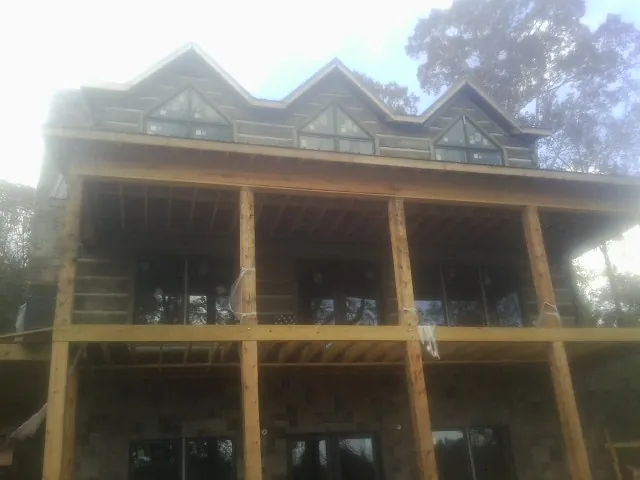 Dormers and porch framing on a large log home under construction — Roof Coating work by our crew in Lake Oswego