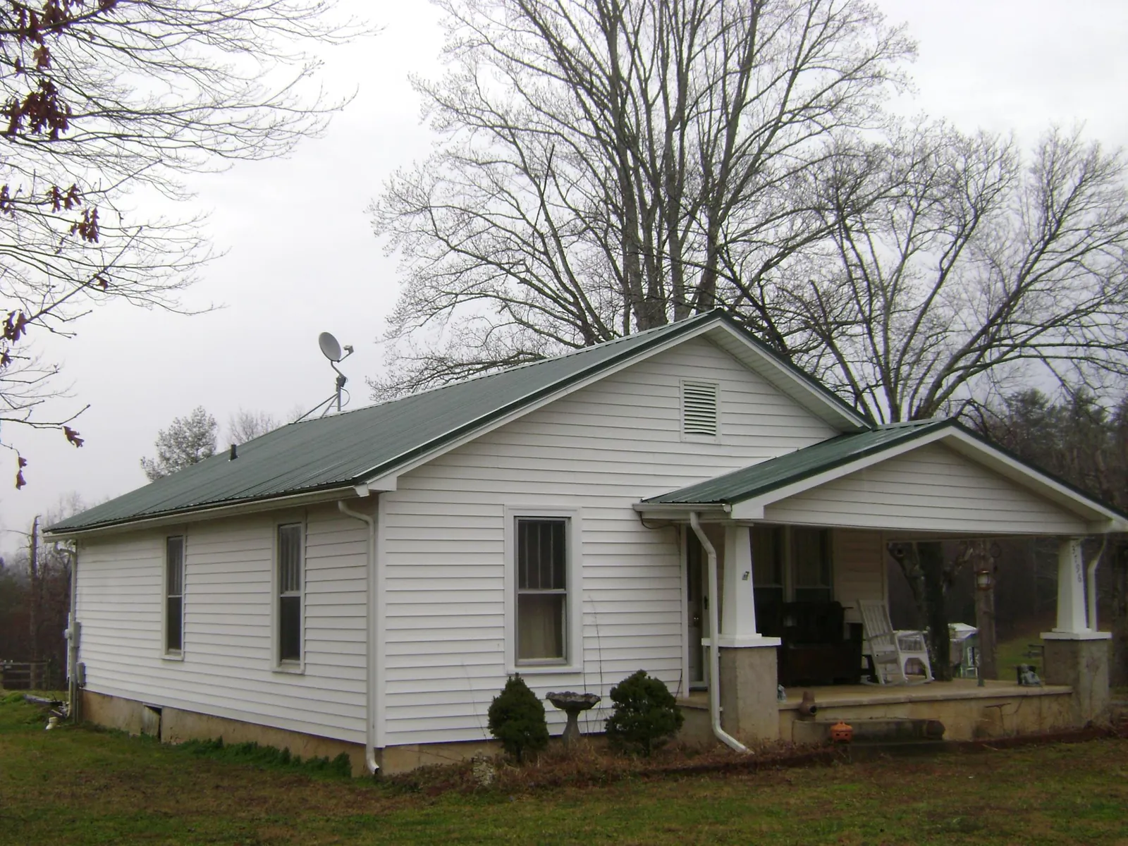 Green metal roof on a white bungalow with a side porch in Lake Oswego