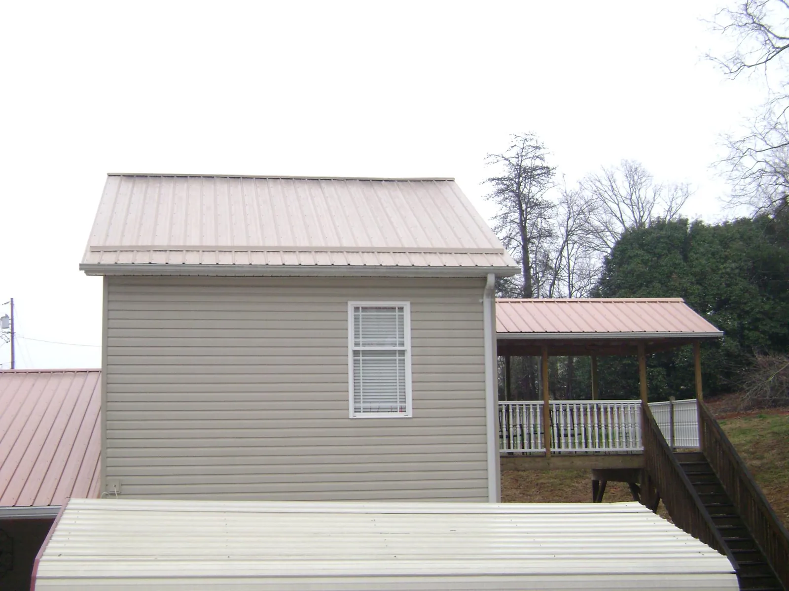 Tan metal roofs on a two story addition and attached porch, from a Roof Replacement job in Lake Oswego