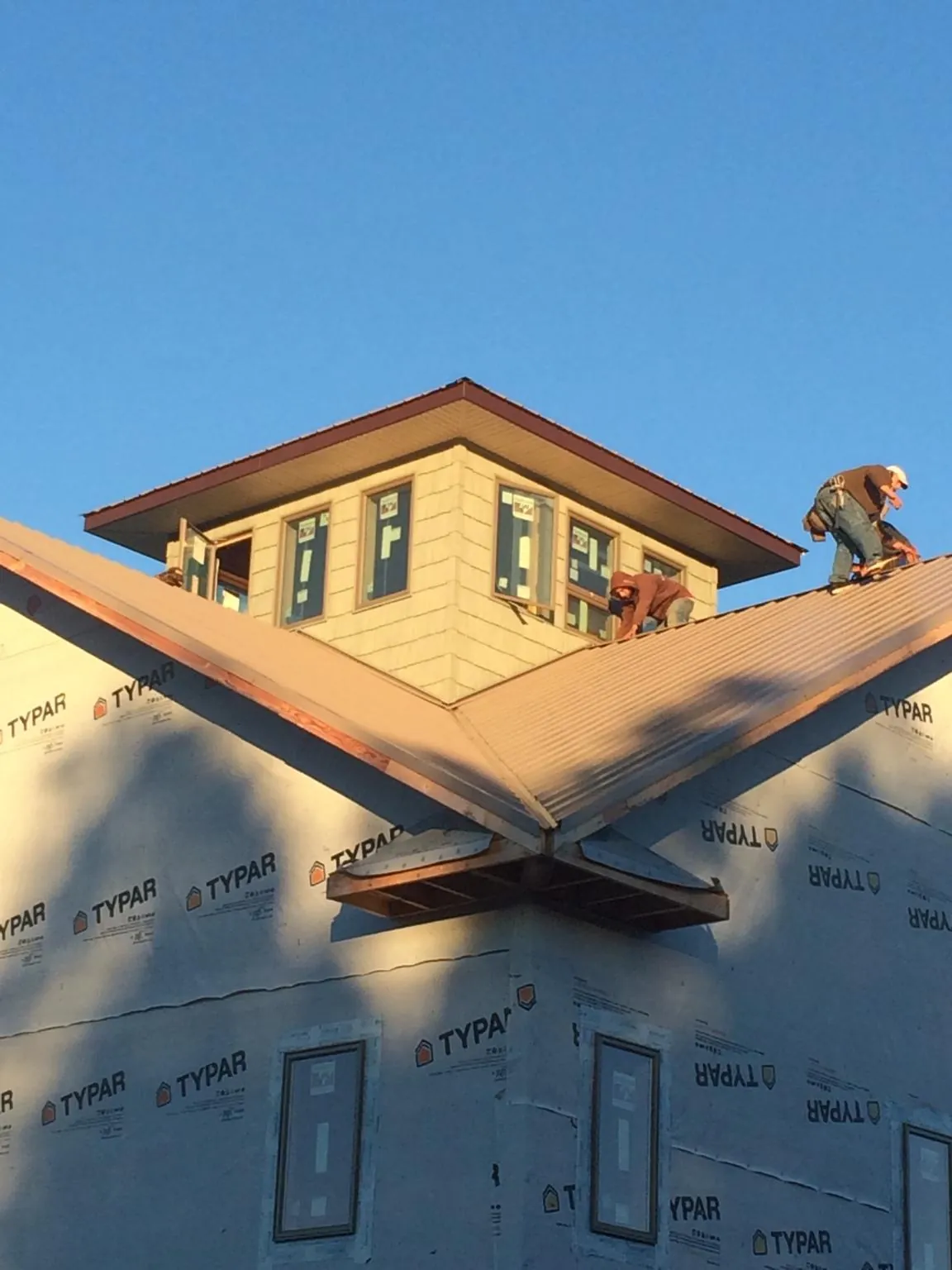 Roofers working around a rooftop cupola on a new metal roof at sunset — Roof Waterproofing in Lake Oswego by Roofing Brothers